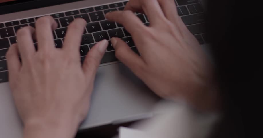 Woman's hands type on a laptop