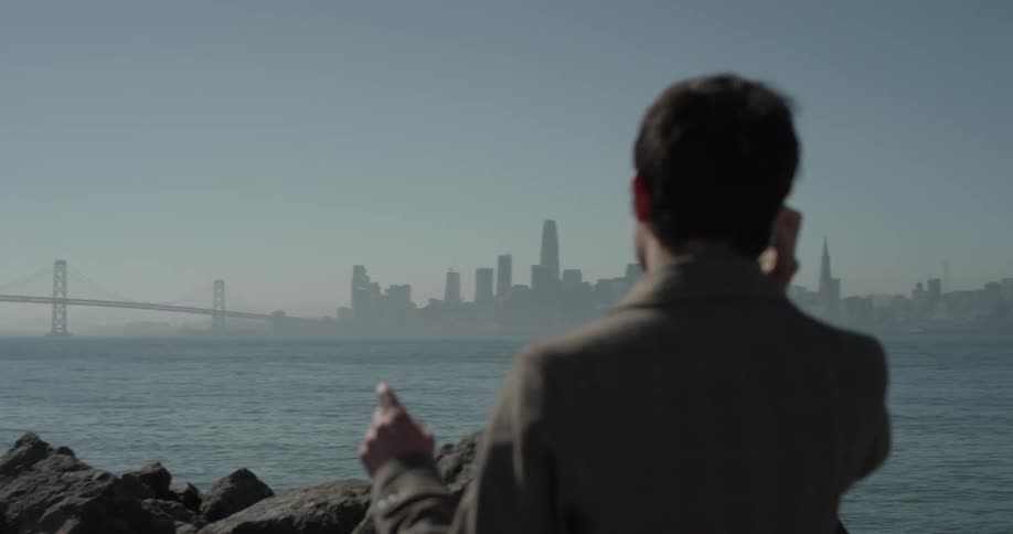 A man standing by a cliff talking on the cell phone