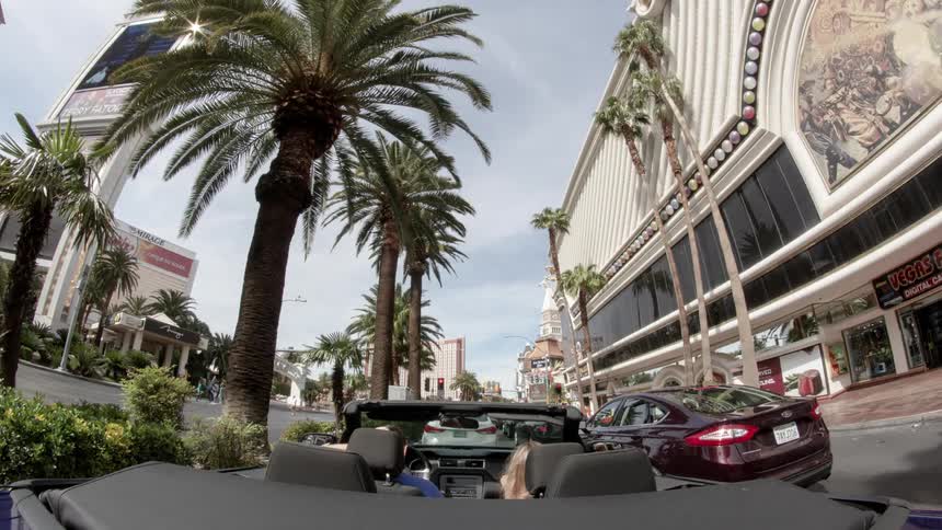 A man and a woman in a convertible on the las vegas strip