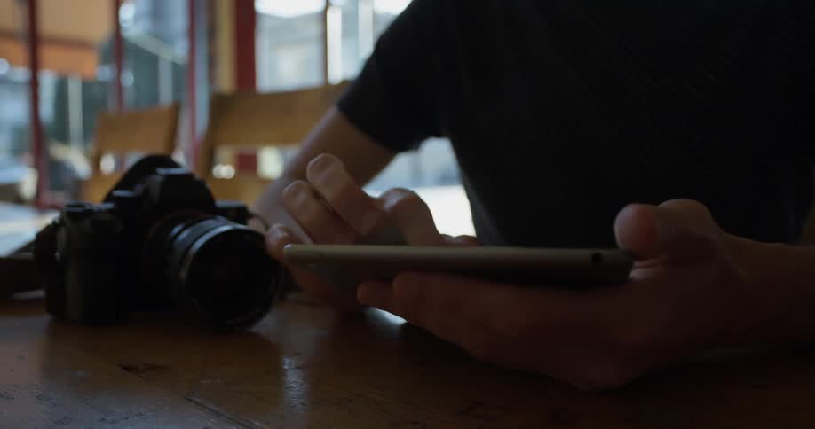 Person sits at a table scrolling on a phone