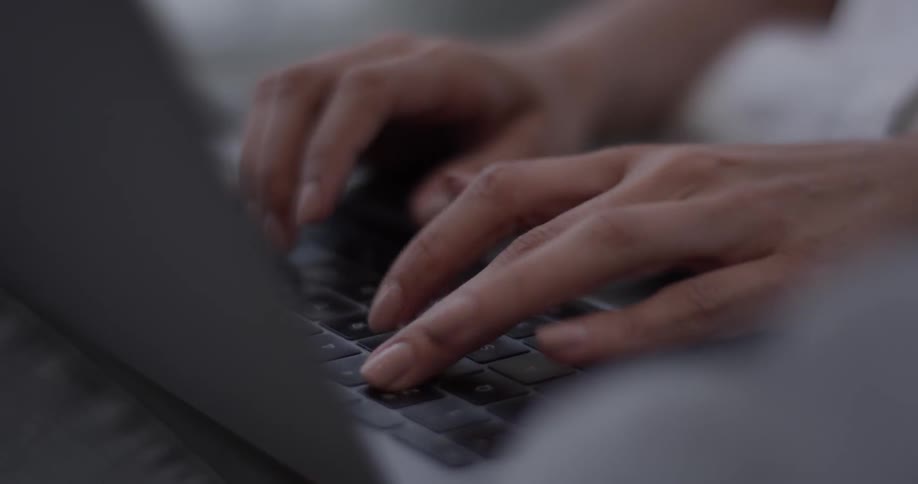 Person sits at a desk and types on a laptop