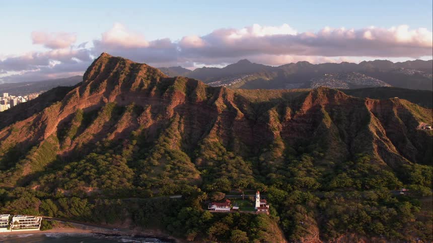 Zooming out at a beautiful landscape of mountains trees ocean clouds and blue skies with a city and roads