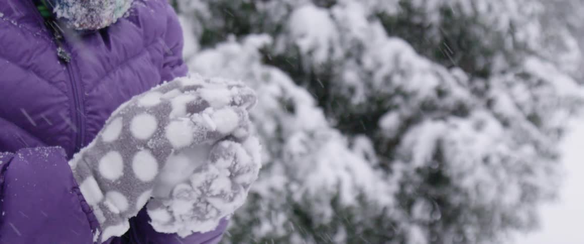 A woman forming a snowball in her hands on a snowy day