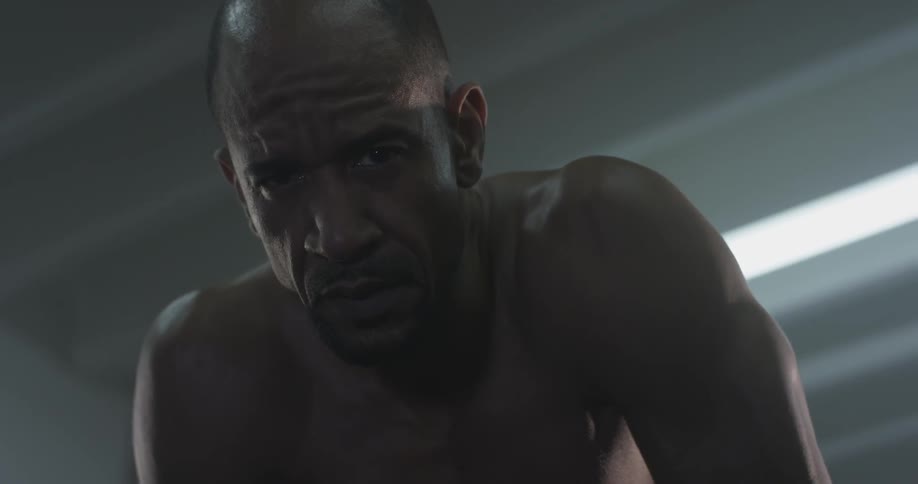 A man looking down at the ground in a gym