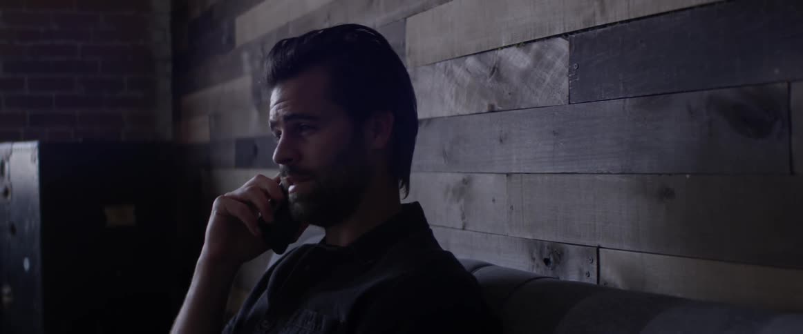 A man answering a phone call on a couch