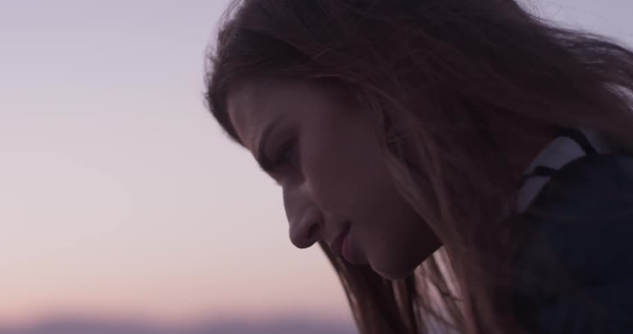 A woman looks down at the ground as if thinking