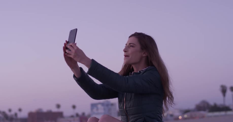 A woman on a video call uses her phone to take a selfie