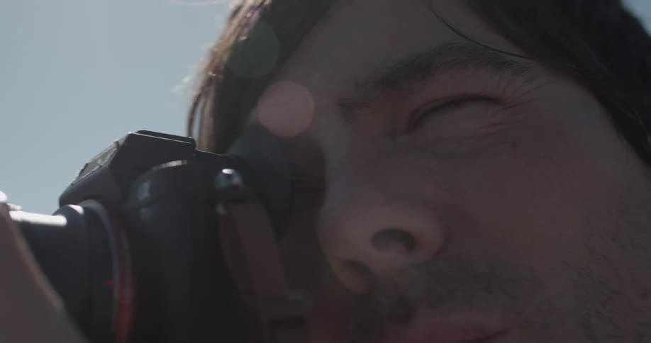 A man looking through a camera lens