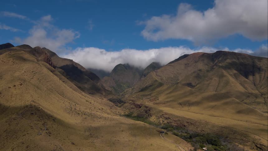 Aerial shot of some hills with clouds in the background