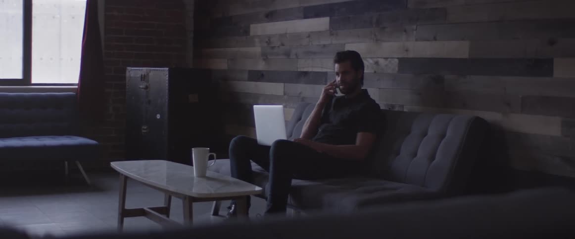 A man sitting on a couch using a laptop