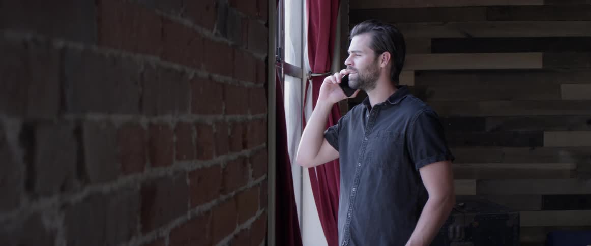 Man staring out the window while talking on a phone