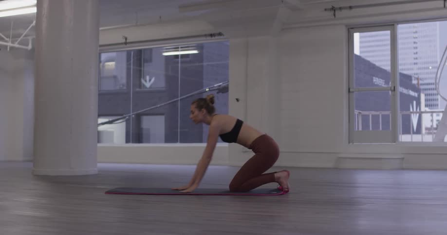 A woman places a yoga mat on the floor