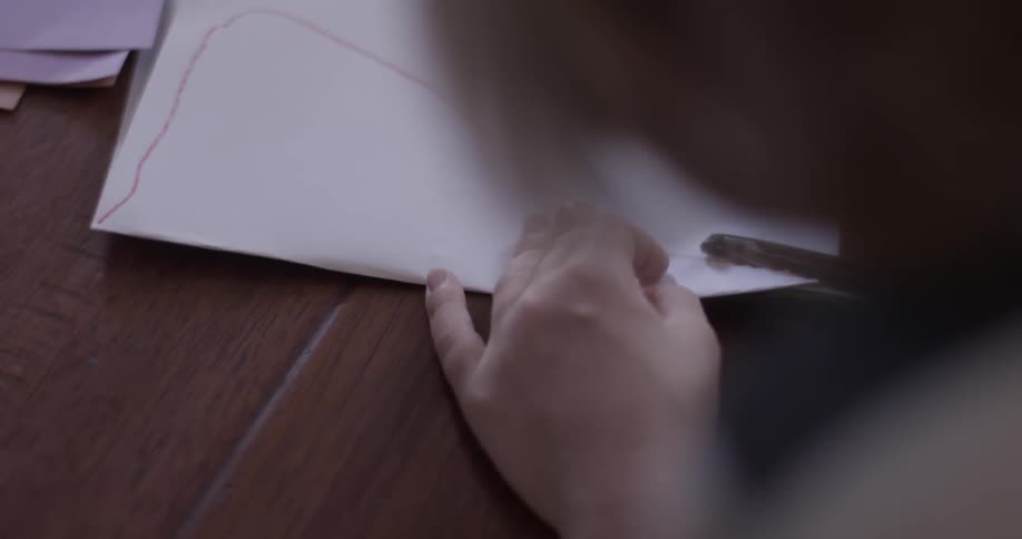 A child is cutting shapes out of a white sheep of paper with lines drawn to follow
