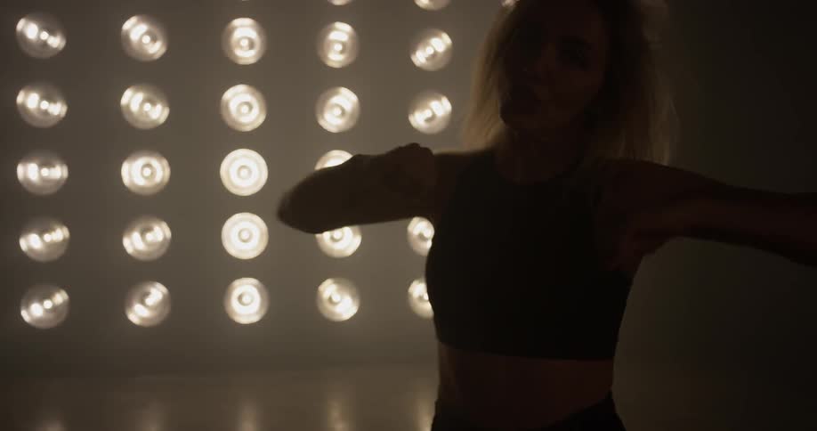 Woman dances in front of a wall of lights