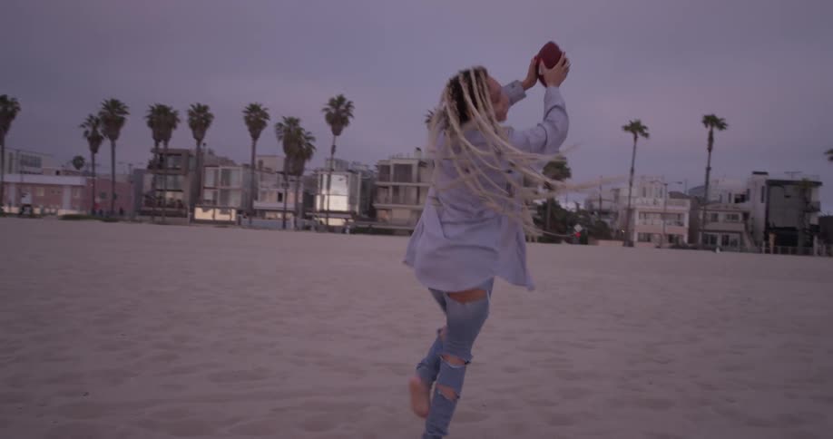 Woman catching a football at the beach