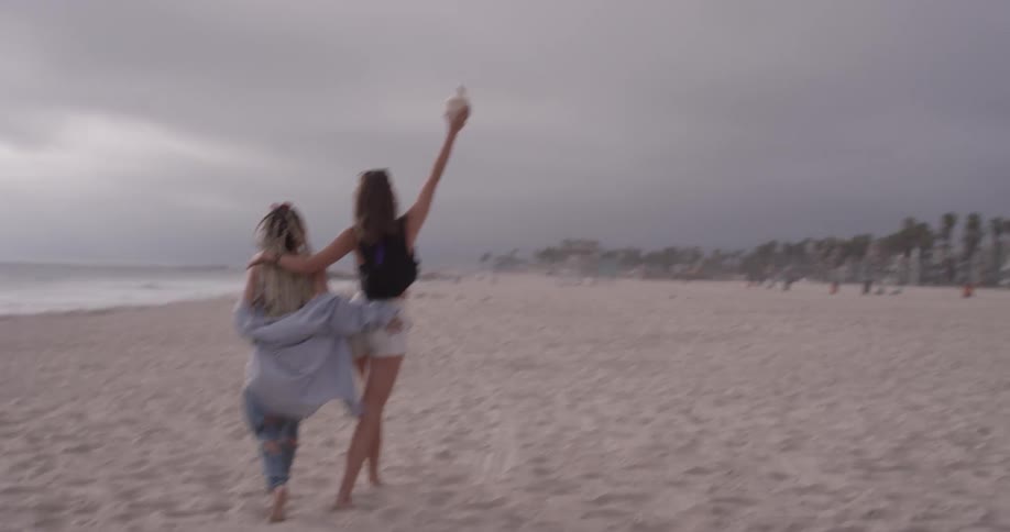 Two women walk on the beach hugging
