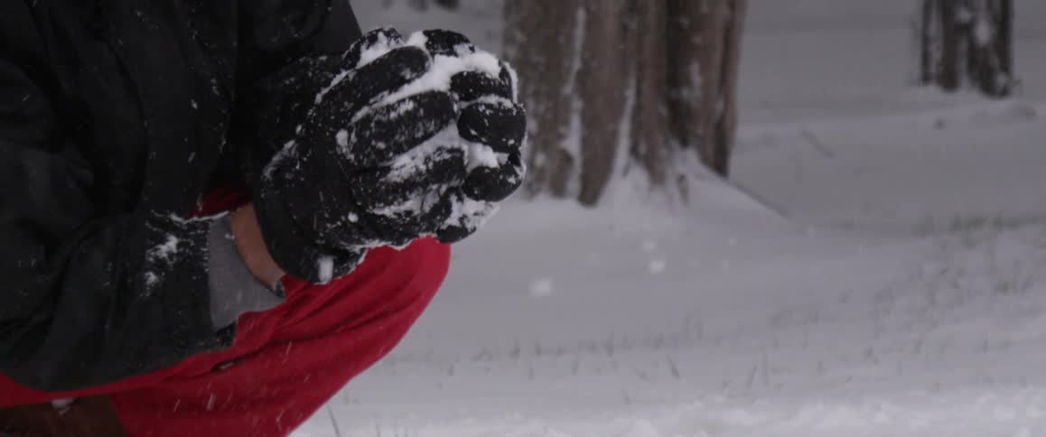 Gloved hands forming a snowball