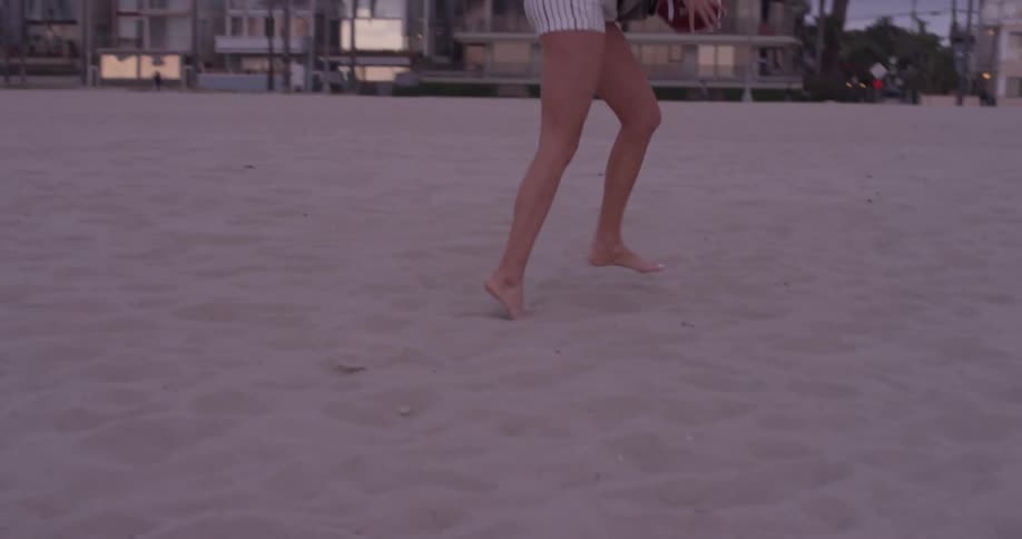 A woman tries to catch a football but it drops to the sand