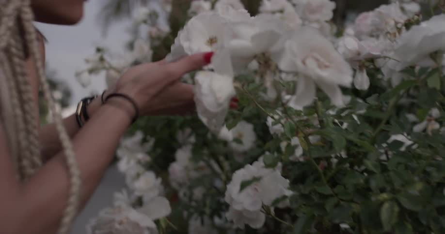 Two women smelling flowers outdoors