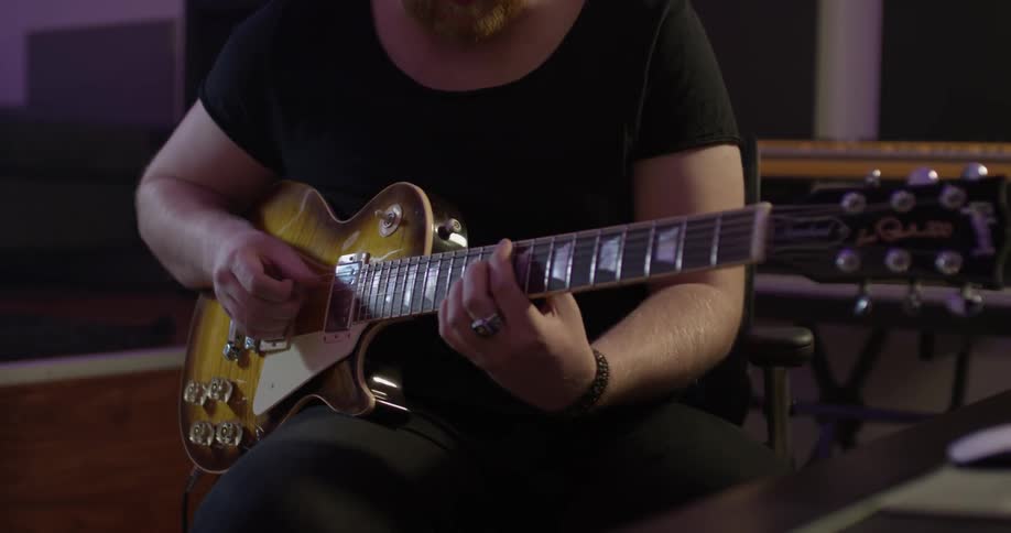 A man playing a guitar in a studio