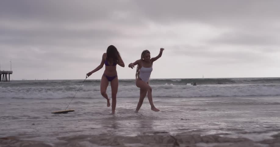 Two woman jump around in the shallow ocean water