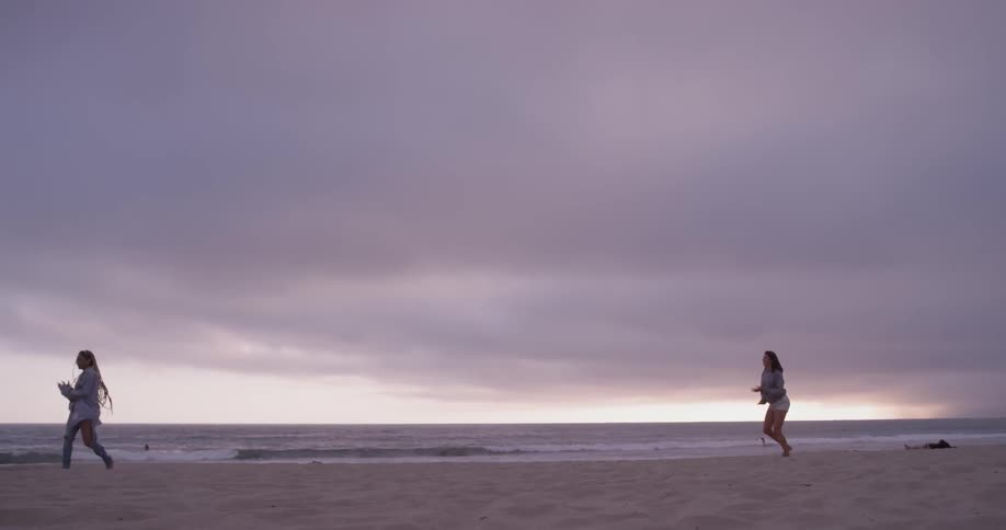 Two women are throwing a football near the beach