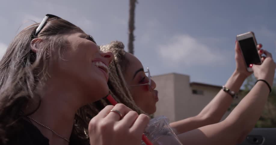 Two women are taking pictures while in a car