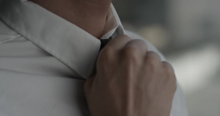 Man pushes knot on his tie