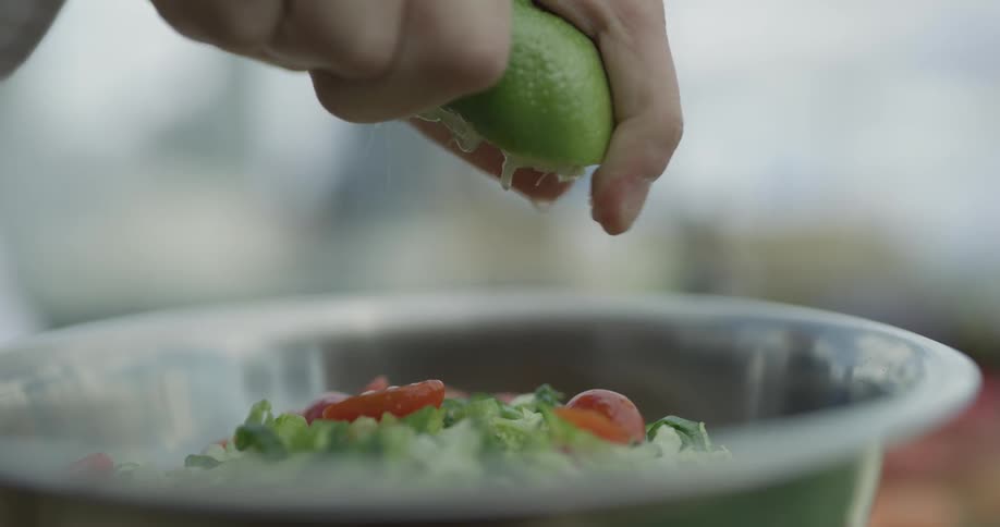 Person squeezes lime onto bowl of salad