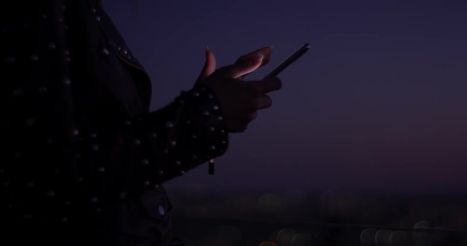 A woman is on her phone outside in the dark