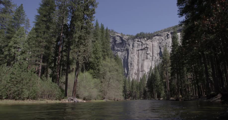 River flows past cliff and tree lined shore