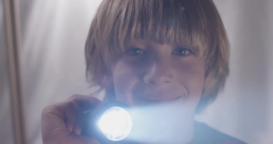 Smiling child shines a light at camera