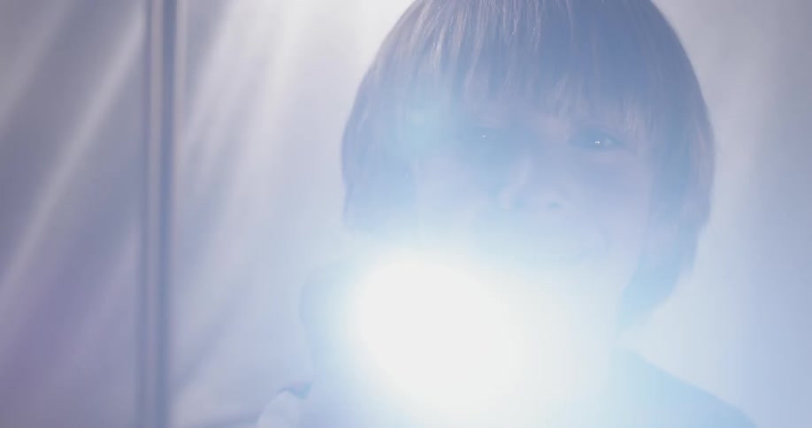 A child moves his flashlight around and shines it into the camera while smiling inside of his fort