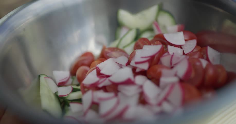 Cucumbers onions and tomatoes are put into a metallic mixing bowl