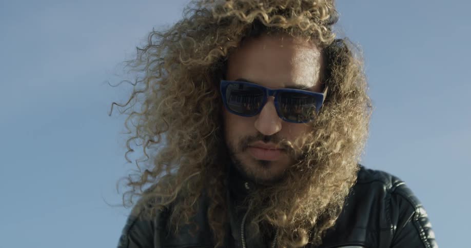 Man looks down at camera while hair blows in the wind