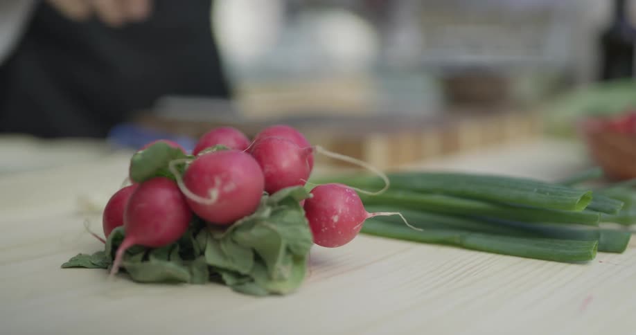 A man grabbing a radish from a bundle