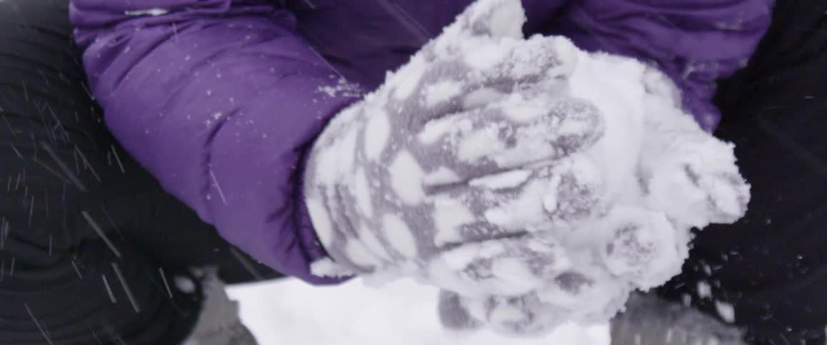 Gloved hands forming a snowball