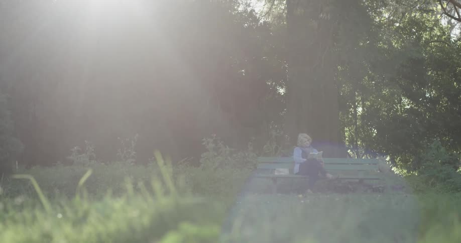A woman is reading while sitting on a bench