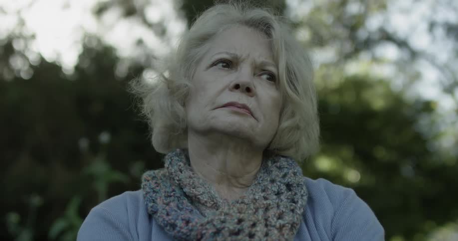 A woman is looking disappointed and contemplative while sitting at a park