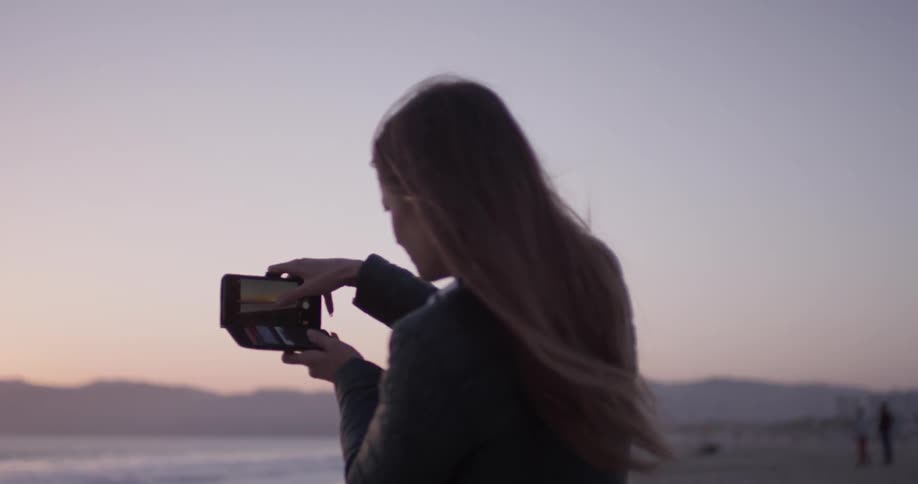 Woman taking a photo of the beach with her cell phone