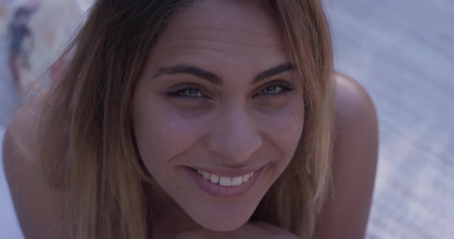 A woman lays belly down on the ground looking up and smiling