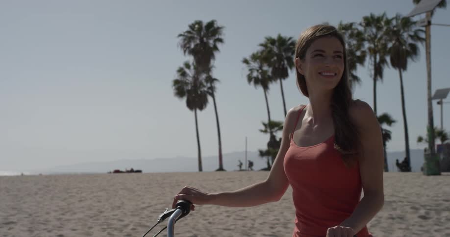 A woman stands by a bike smiling brightly