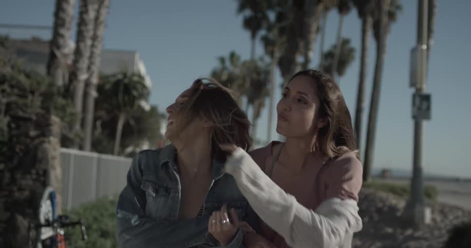 Two women walk arm in arm down a path