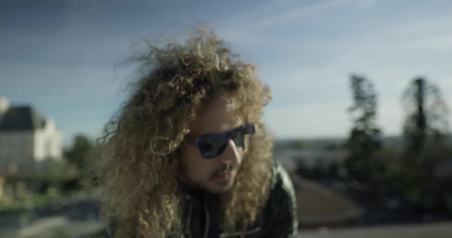 A long haired man playing on a keyboard outside