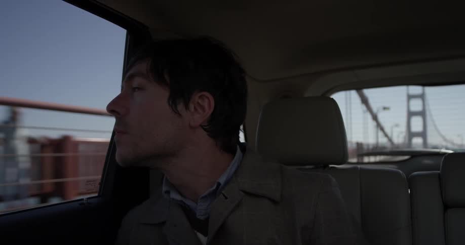 A man riding in a car over a bridge