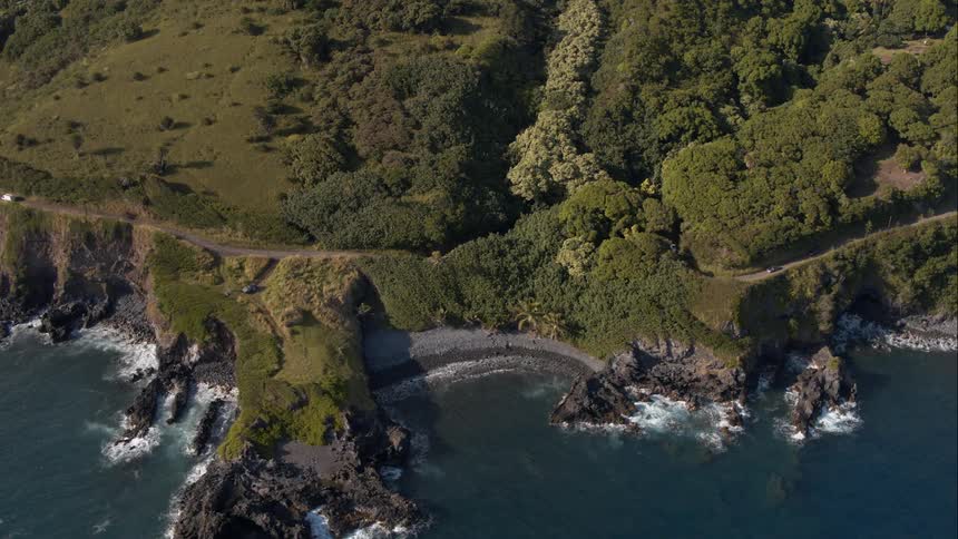 A car drives down a twisting coastal road
