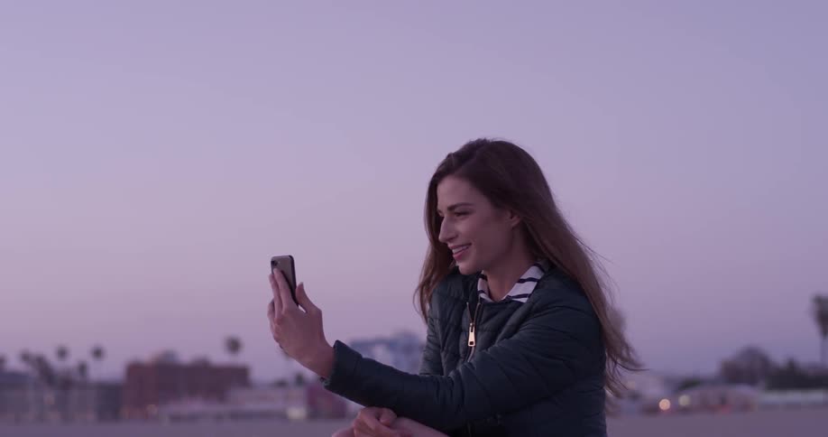 Woman waving at someone on a phone