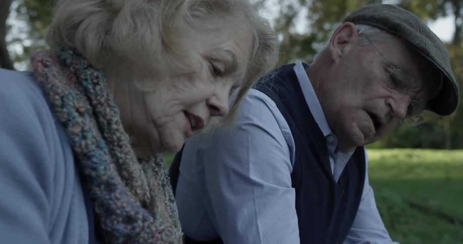 An old couple sits together under a tree