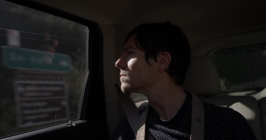 A man riding in the back of a car