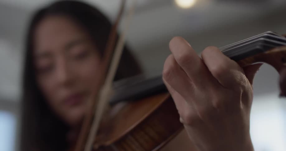 A woman is playing a violin inside in daylight